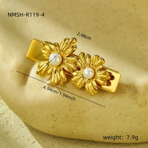 Detail view of golden sunflower hair clip with white pearls on a beige ceramic base