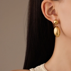 Poliert goldene Tropfenohrringe aus Titanstahl, getragen für einen minimalistischen Look
