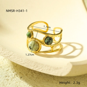 Dettaglio macro di anello aperto placcato oro 18k con tre pietre verdi sul display