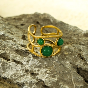 Dettaglio macro di un anello aperto placcato oro 18k con texture e pietre naturali verdi