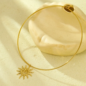 Collana con ciondolo a sole in acciaio inossidabile placcato oro 18K su sfondo sabbia