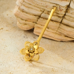 Barrette à cheveux fleur ajourée dorée élégante avec un zircon sur un fond de pierre naturelle