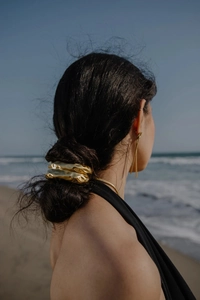 Detailed view of an 18K gold geometric hair tie with irregular hammered lava texture