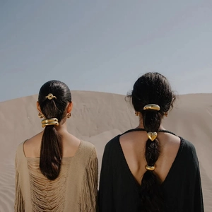 Macro view of geometric 18K gold-plated hair ties and clips styled on models in desert