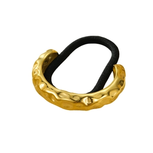 Minimalist gold stainless steel hair tie with irregular lava texture on white background