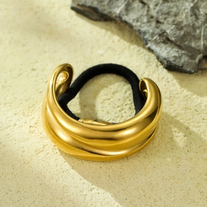 Elegant gold curved metal textured hair tie with black elastic band on stone background