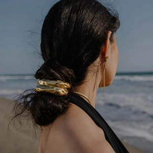 Golden irregular hammer textured hair cuff and long dangle earrings on a sunny beach