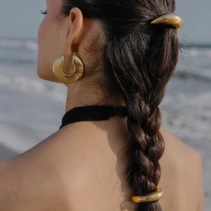 Polished gold curved metal hair wrap and hoop earrings set on brunette braided hair