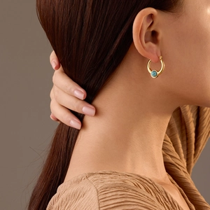 Elegante 18K vergoldete U-Ohrringe mit Türkissteinen an einem Model getragen