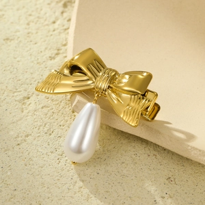 Golden bow hair clip with white pearl pendant on elegant minimalist stone background