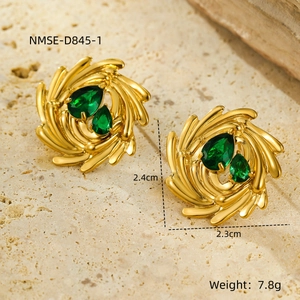 Vista macro de pendientes de espiral dorados con piedras verdes de gota y medidas