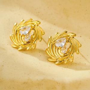 Detalle de pendientes de botón dorados en espiral con circonitas en forma de gota