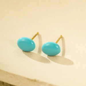 Detailed close-up of small turquoise enamel bean studs with 18K gold plated stainless steel