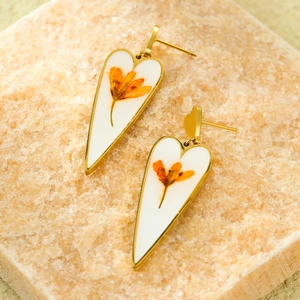 Detail of gold heart drop earrings with white resin and preserved orange flowers