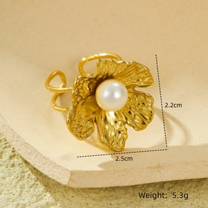 Détail d'une bague fleur dorée avec texture de pétales et incrustation d'une perle