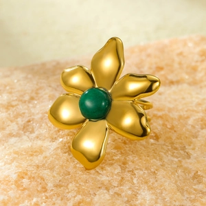 Macro detail van 18K vergulde bloemring met groene steen op een natuurlijke mineraalrots