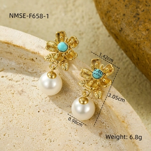 Detalle macro de pendientes de flor en oro de 18k con turquesa y perlas blancas