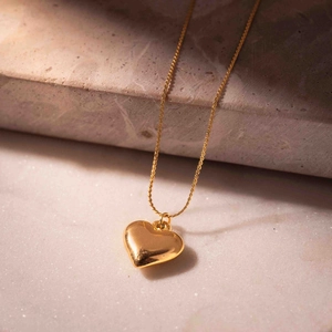 Minimalist 3D heart pendant necklace with polished gold finish on marble stone base