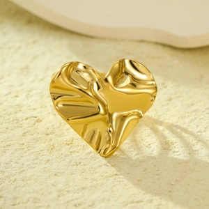 Elegante anello a cuore pieghettato dorato con trama metallica liquida su sabbia