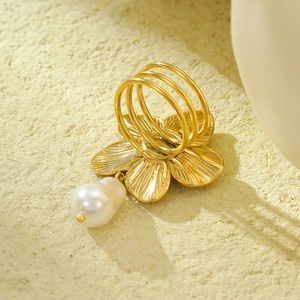 Detail of a gold flower ring featuring a baroque pearl pendant and triple band design