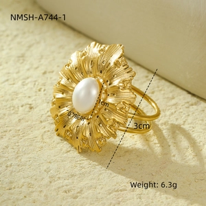 Macro detail of vintage gold floral ring with pearl inlay and engraved petal texture