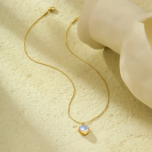 18K gold plated stainless steel necklace with heart-shaped moonstone pendant on stone