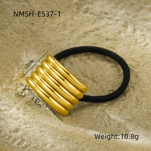 Detail view of a golden multi-layer metal hair tie with a textured beige stone background