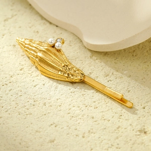 Pince à cheveux coquillage doré avec perles et strass sur fond texturé minimaliste