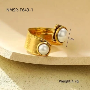 Detalle de textura martillada en un anillo ancho dorado con elegantes perlas blancas