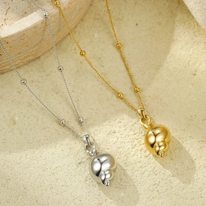 Gold and silver conch pendant necklaces on stone background with polished bead chains
