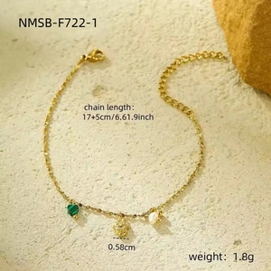 Detailopname van de gouden armband met groen hart, Hamsa-hand en een natuurlijke parel