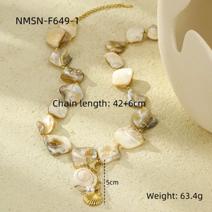 Dettaglio della collana di conchiglie crema con pendente stella marina dorata e perla su sfondo beige