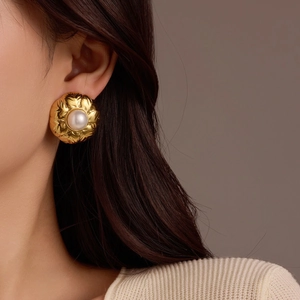Detalle de pendiente floral de oro de 18k con perla central en una modelo