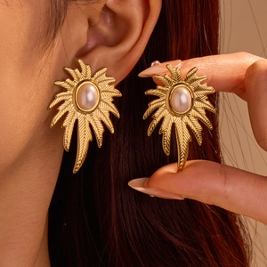 Detalle macro de los pendientes de pétalos en oro de 18k con perla y metal texturizado