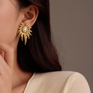 Primer plano detallado de pendientes de pétalos bañados en oro de 18k con perla blanca