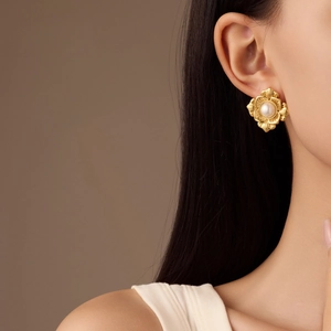 Pendientes de pétalos en oro de 18 quilates con perla en una modelo femenina