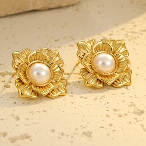 Detalle de pendientes de pétalos en oro de 18k con perlas sobre base de piedra