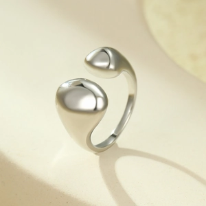 Gros plan de la bague argentée style métal liquide sur une surface en pierre mate