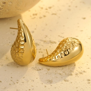 Detalle de pendientes de gota en oro de 18K con textura de metal martillado y pulido fino