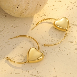 Detailaufnahme goldener Herz-Ohrringe auf Steinsockel mit hochglanzpoliertem Finish