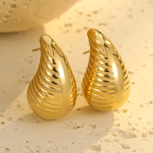 Detalle de pendientes chapados en oro 18K con textura de gota de agua sobre piedra