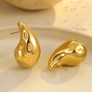 Primer plano de pendientes de acero inoxidable dorado con textura de lava fundida