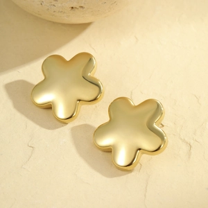 Boucles d'oreilles fleurs dorées minimalistes en acier poli sur un support en pierre