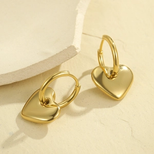 Poliertes Gold Herz-Ohrringe auf Steinhintergrund, Edelstahl-Schmuck für Damen