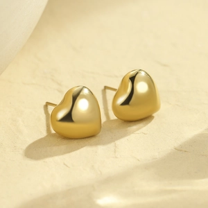 Vue macro de boucles d'oreilles cœur dorées avec une finition miroir brillante