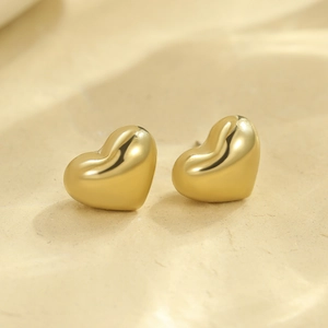 Gros plan de boucles d'oreilles cœur en or poli avec une finition miroir lisse