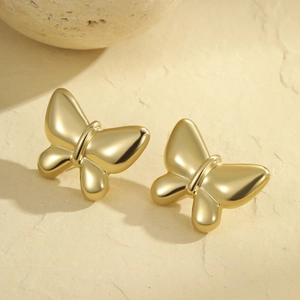 Gros plan de boucles d'oreilles papillon dorées minimalistes au fini mat poli