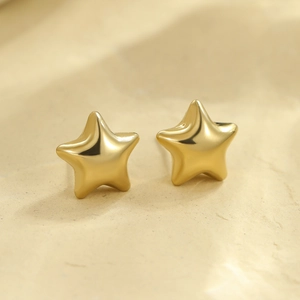 Vue macro de boucles d'oreilles étoiles 3D en acier inoxydable doré poli sur fond texturé
