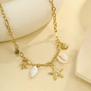 Gold chain necklace with shell and starfish charms on a ceramic stand for summer vacation