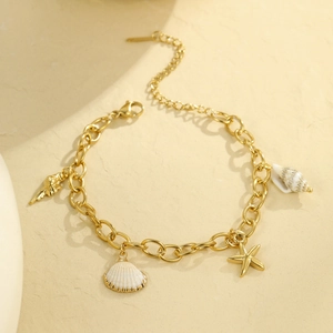 Golden ocean charm bracelet with starfish and shell pendants on a sandy background